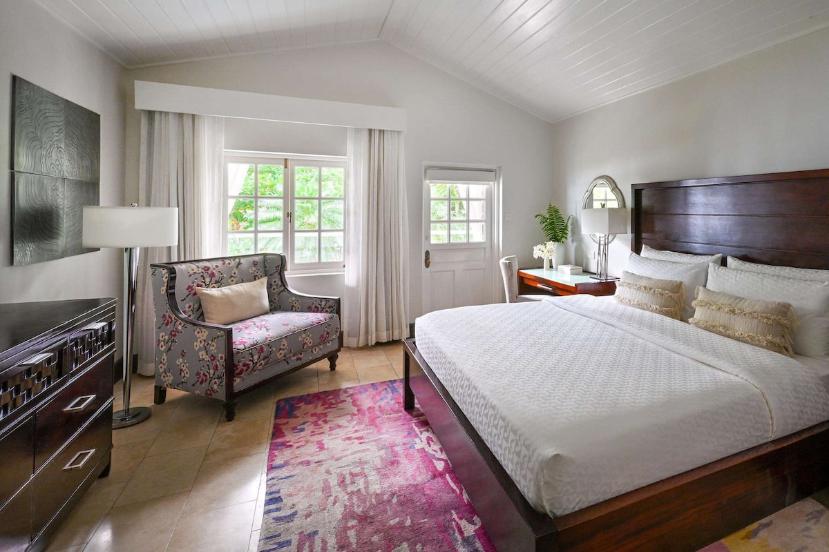 A bedroom with a large bed, a dresser, a chair, and a desk.