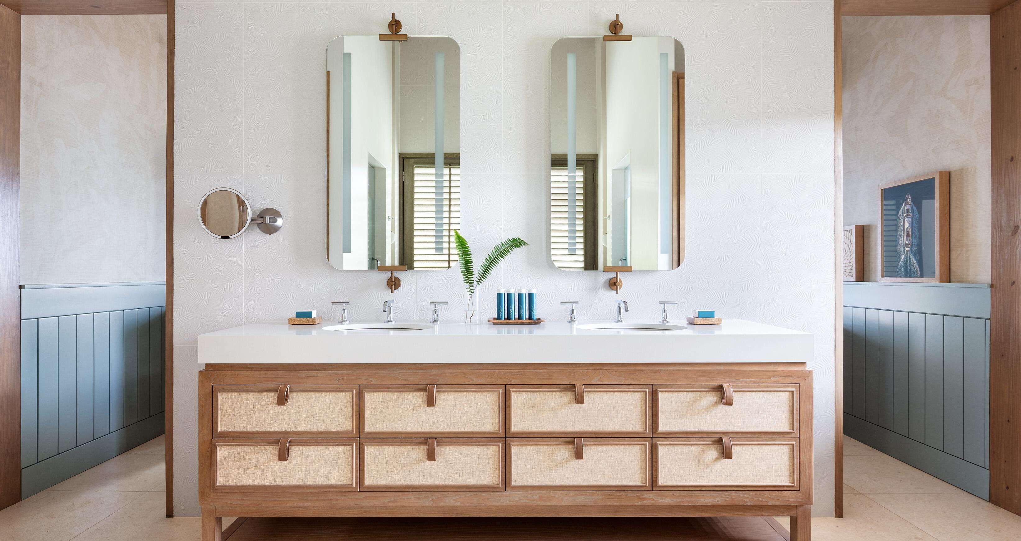 Une salle de bain avec un meuble-lavabo blanc, deux miroirs, un évier et un meuble en bois doté de tiroirs.