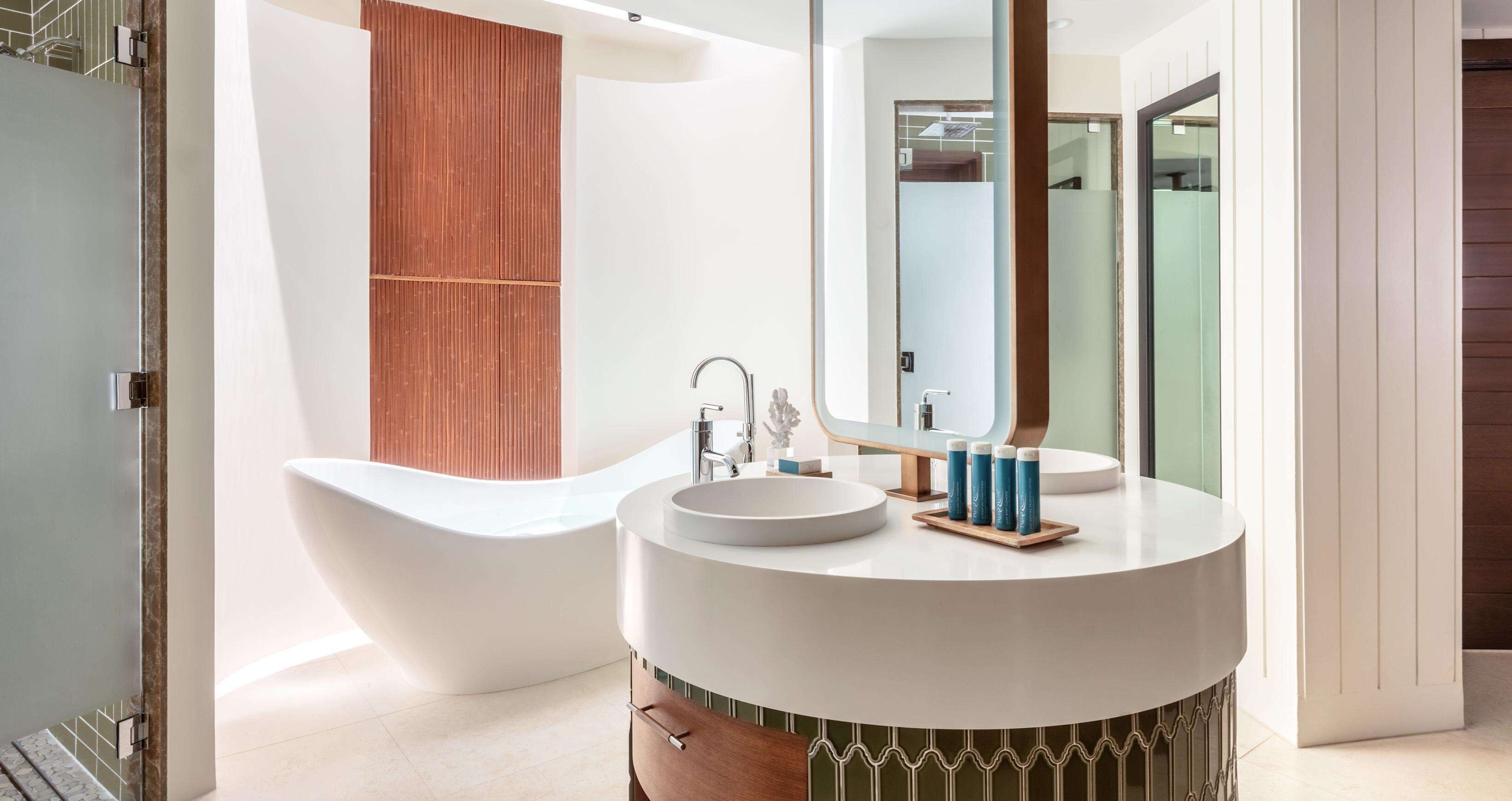 A modern bathroom with a freestanding bathtub, a round vanity with a mirror, and a wooden panel wall.