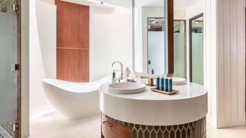 A modern bathroom with a freestanding bathtub, a round vanity with a mirror, and a wooden panel wall.
