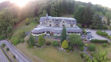 Situated amidst lush greenery, this two-story building features a covered porch and several windows on the upper floor.