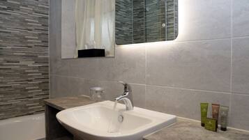 A bathroom with a white sink, a glass shower enclosure, and a mirror above the sink.