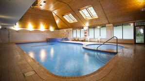 An indoor swimming pool with wooden ceiling and skylights, surrounded by tiled flooring and furnished seating. - Waterloo Hotel Lodge (Betws-Y-Coed)