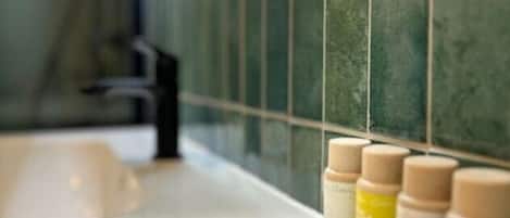 A bathroom with a white sink, green tiled walls, and a mirror.