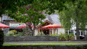 A restaurant with outdoor seating, stone walls, and red umbrellas. - Waterloo Hotel Lodge (Betws-Y-Coed)