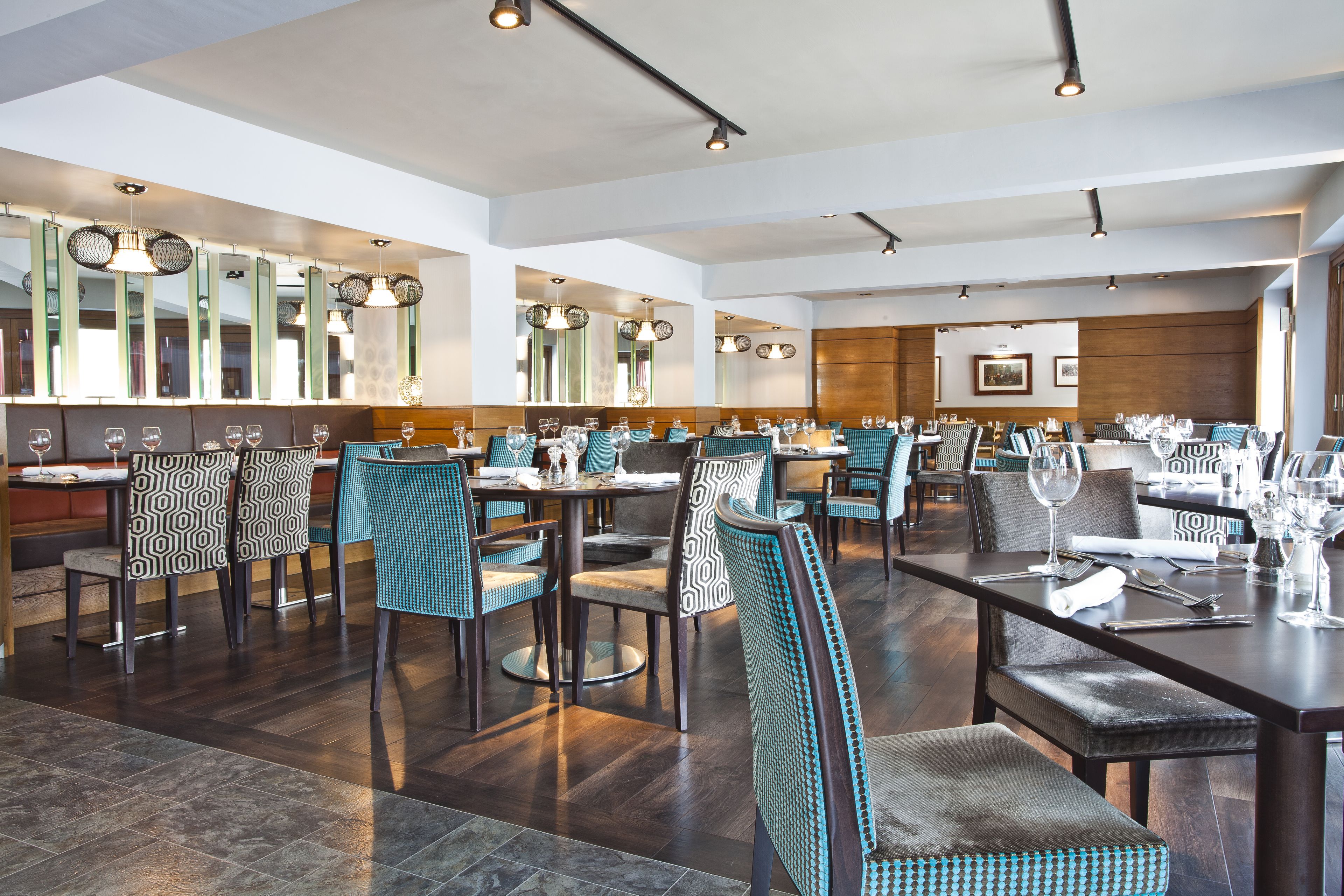 Un restaurante espacioso con techos altos, iluminación moderna y diferentes opciones de asientos, como cabinas y mesas.