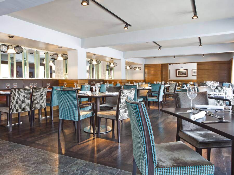 A spacious restaurant with high ceilings, modern lighting, and a variety of seating arrangements including booths and tables.