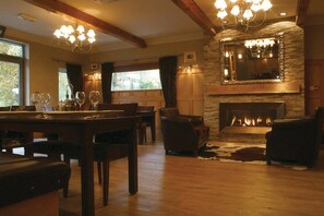 A cozy living room with a fireplace, wooden furniture, and a chandelier. - Waterloo Hotel Lodge (Betws-Y-Coed)