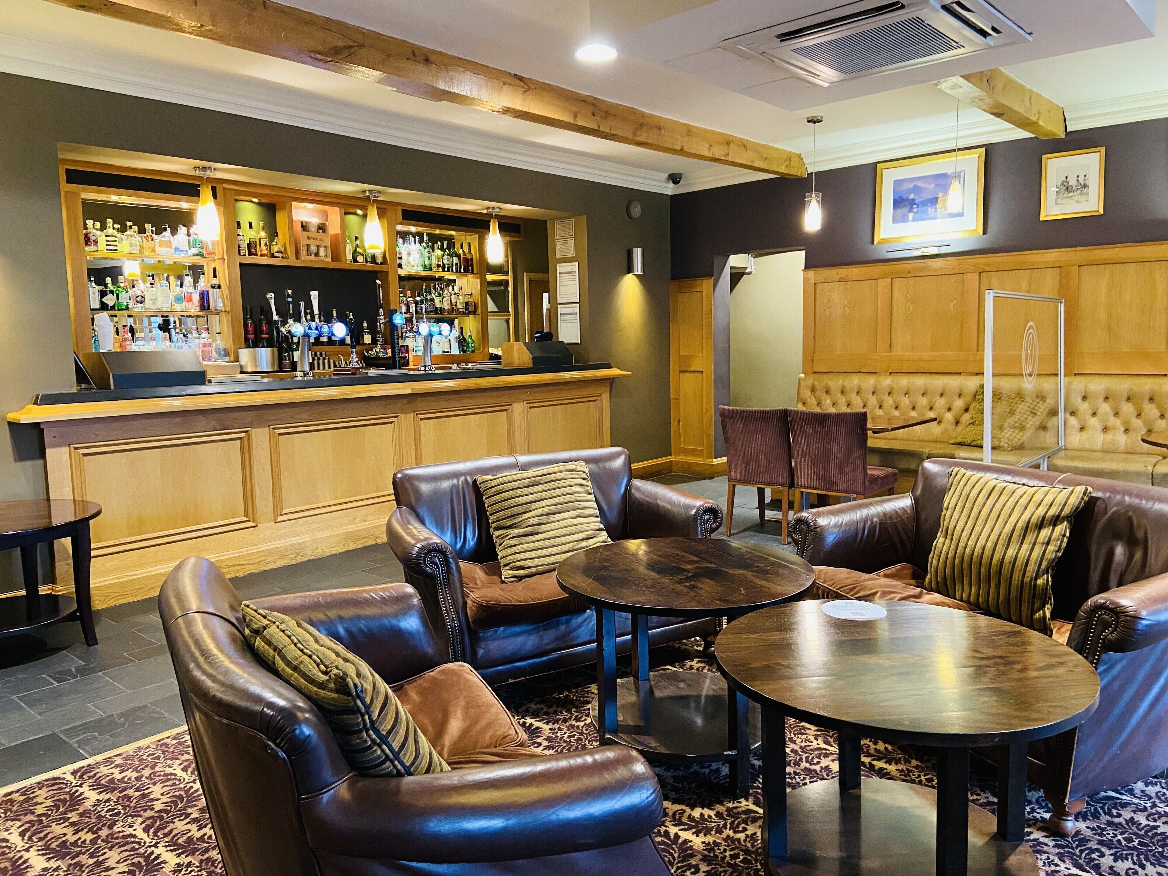 A bar area with leather seating and a bar counter stocked with liquor bottles.