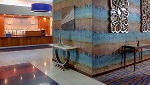 A hotel reception area with a modern design, featuring a reception desk, a blue pendant light, and decorative wall art. - Best Western Aberavon Beach Hotel (Port Talbot)
