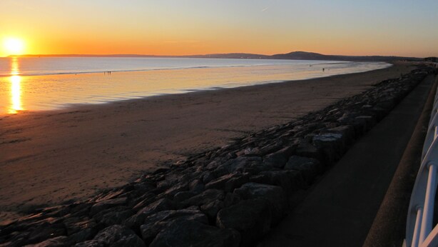 A beach with a rocky shoreline, a clear sky, and the sun setting over the horizon. - Best Western Aberavon Beach Hotel (Port Talbot)