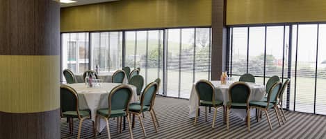 A conference room with tables and chairs, large windows, and a carpeted floor.