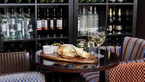 A bar area with a round table, a wooden board with bread, glasses, and bottles of wine. - Best Western Aberavon Beach Hotel (Port Talbot)