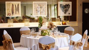 Een elegant gedekte tafel met witte tafellinnen, gouden linten en glazen.