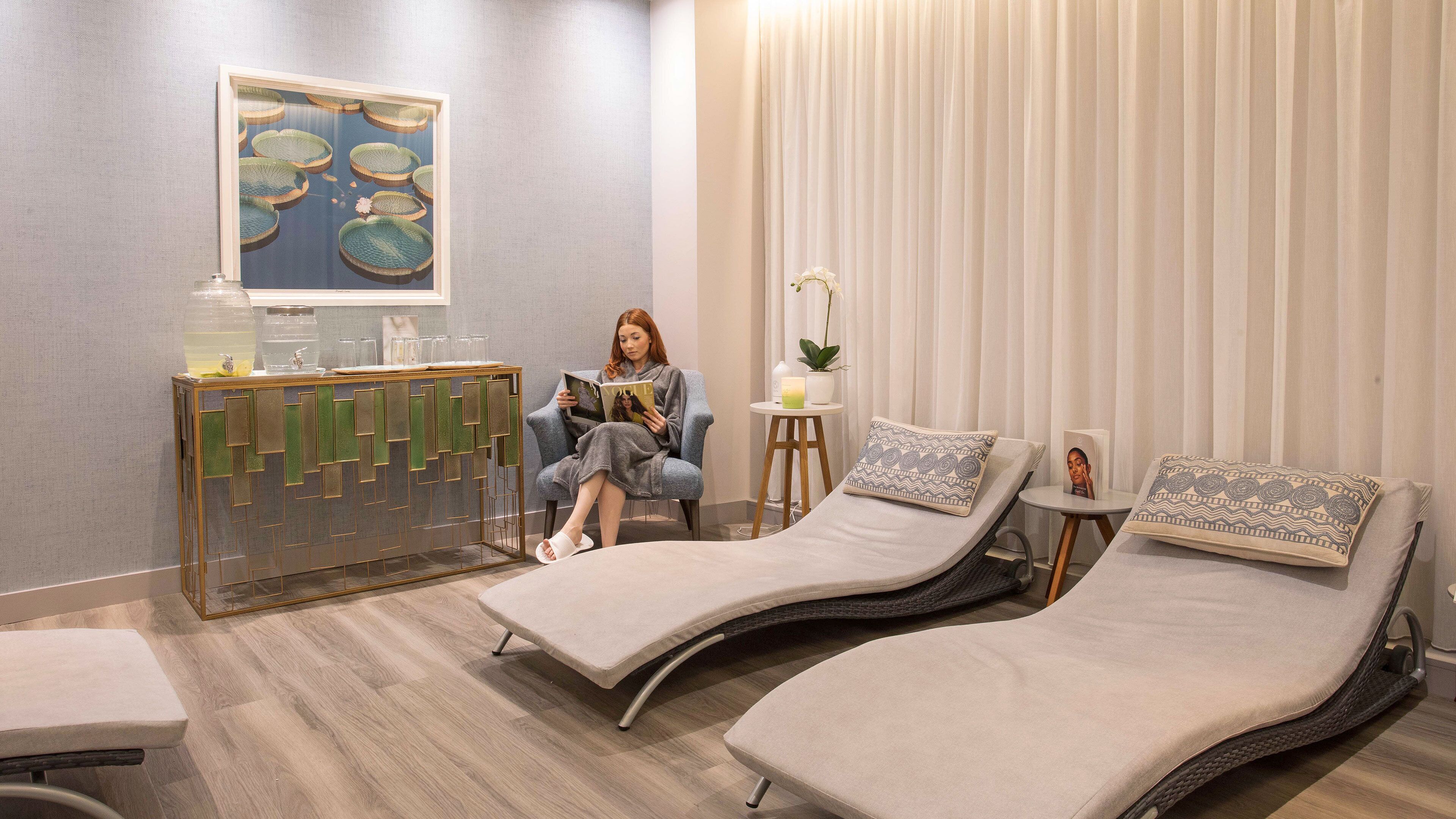 Un spa moderno con una camilla de masaje, un sillón de lectura y una pieza decorativa en la pared.