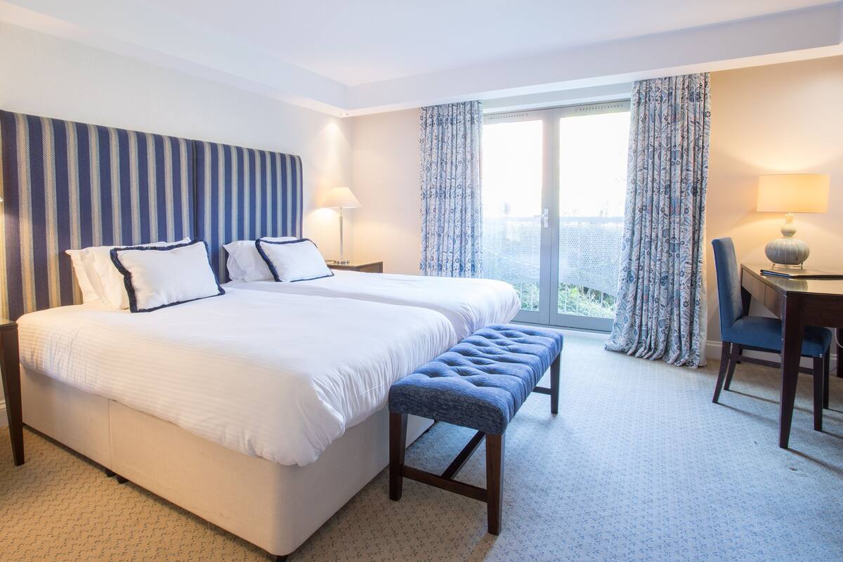 A hotel room with a large bed, two bedside tables, a desk, and a chair.