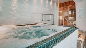 A hot tub with a tiled edge, a metal handrail, and a wooden door leading to a sauna area. - The Wrightington Hotel & Health Club (Wigan)