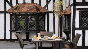 A table set with breakfast items, including eggs, toast, and fruit, in front of a building with exposed timber framing and a tiled roof. - Donnington Manor Hotel (Sevenoaks)