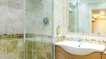 A modern bathroom with a glass-enclosed shower, a sink with a mirror above it, and wooden cabinets.