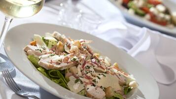 A plate of food with a fork and a glass of white wine on a table.