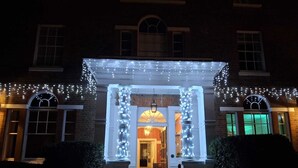 A building entrance with a porch adorned with string lights and two columns. - Moore Place Hotel, BW Signature Collection (Milton Keynes)