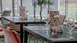 A restaurant setting with tables set for dining, featuring clear glassware and a menu stand. - Moore Place Hotel, BW Signature Collection (Milton Keynes)