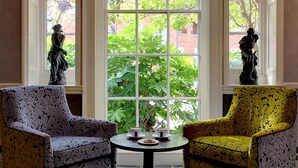 A room with two chairs, a table with a plant and two cups, and a large window with a view of greenery and a brick building. - Moore Place Hotel, BW Signature Collection (Milton Keynes)