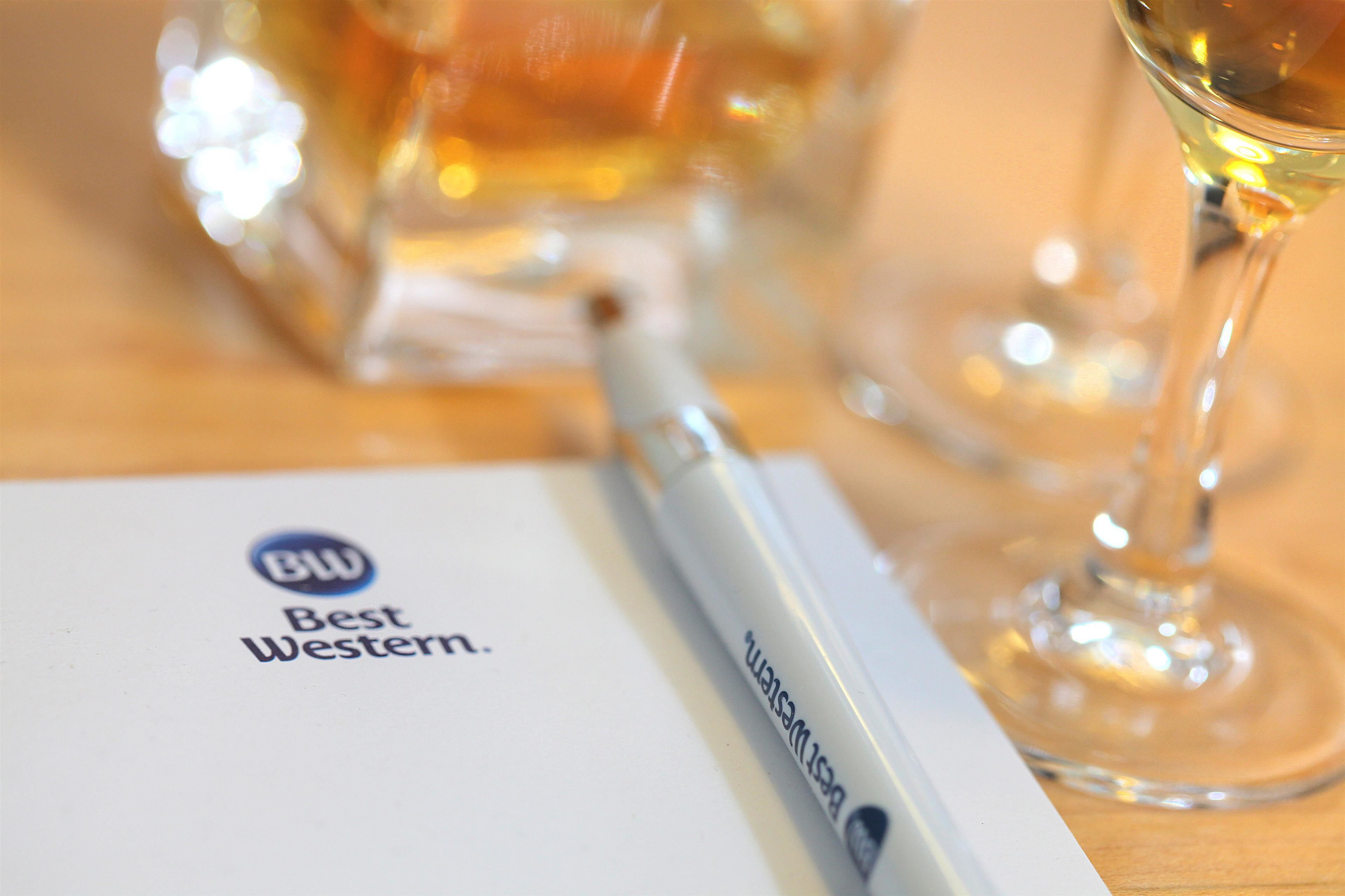A pen, a glass of white wine, and a document with the logo "Best Western."