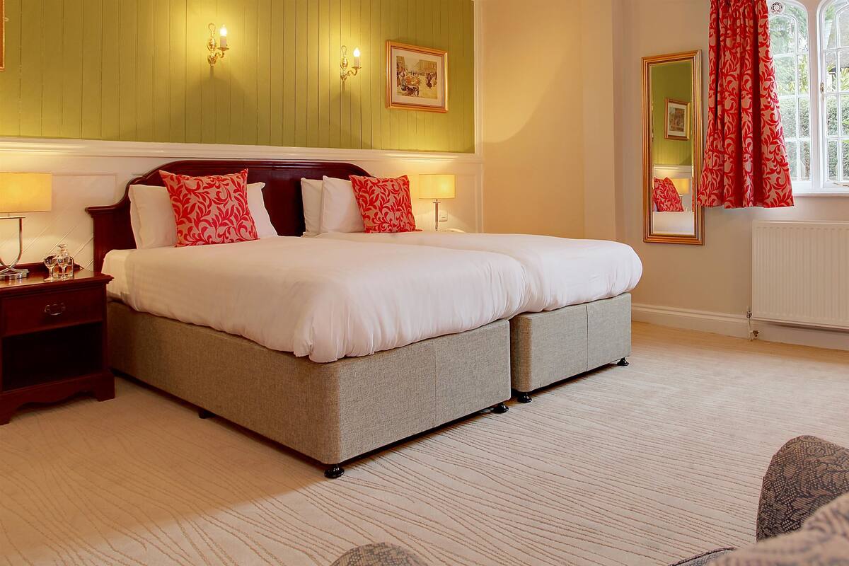 A large bed with a headboard, two bedside tables, and a mirror on the wall.