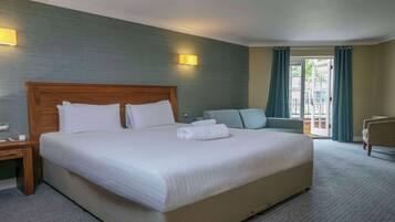 Habitación de hotel con una cama grande, un escritorio, una silla y vistas al exterior.