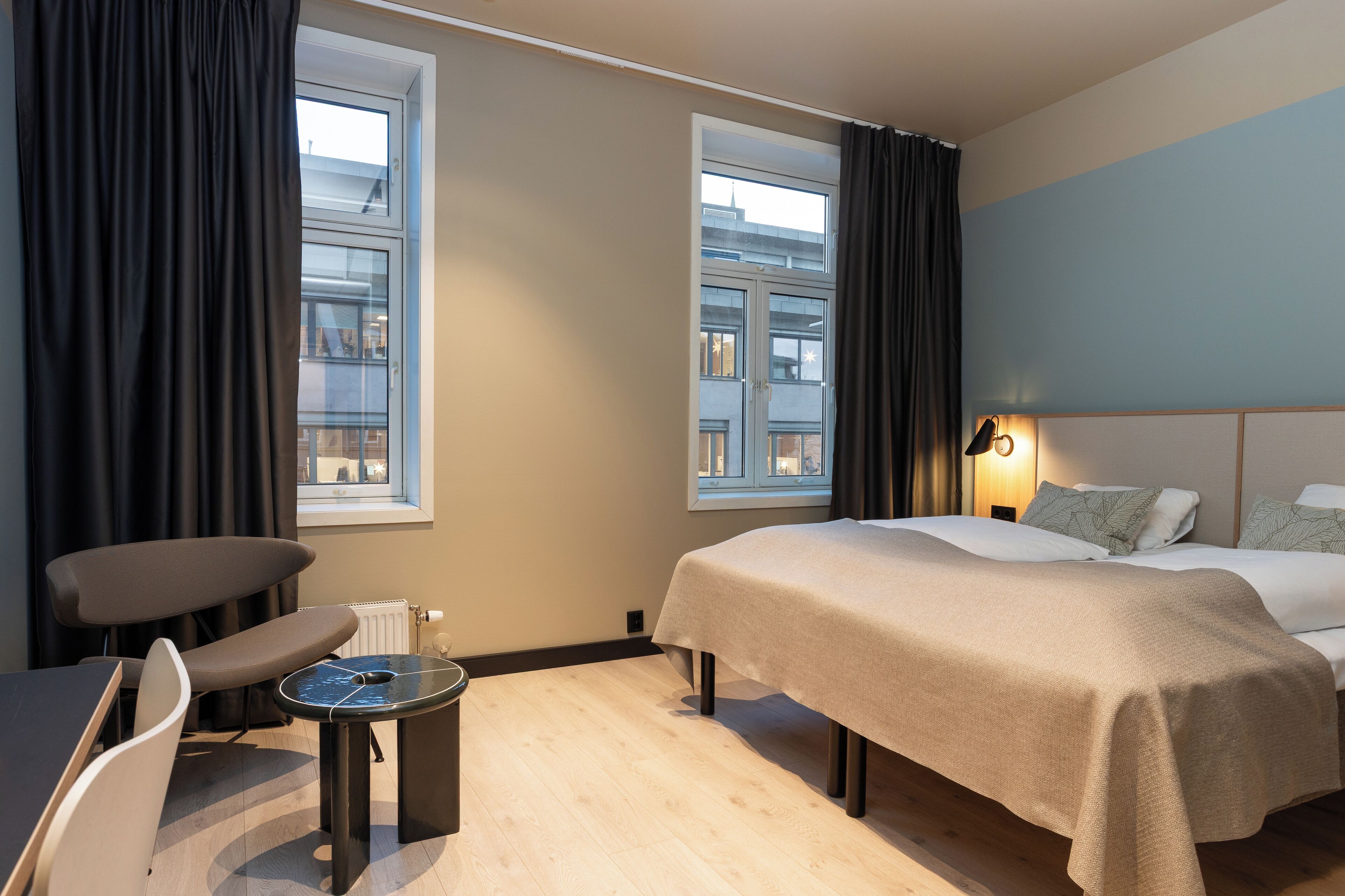 Hotellihuone, jossa on sänky, työpöytä, tuoli ja pieni pöytä.