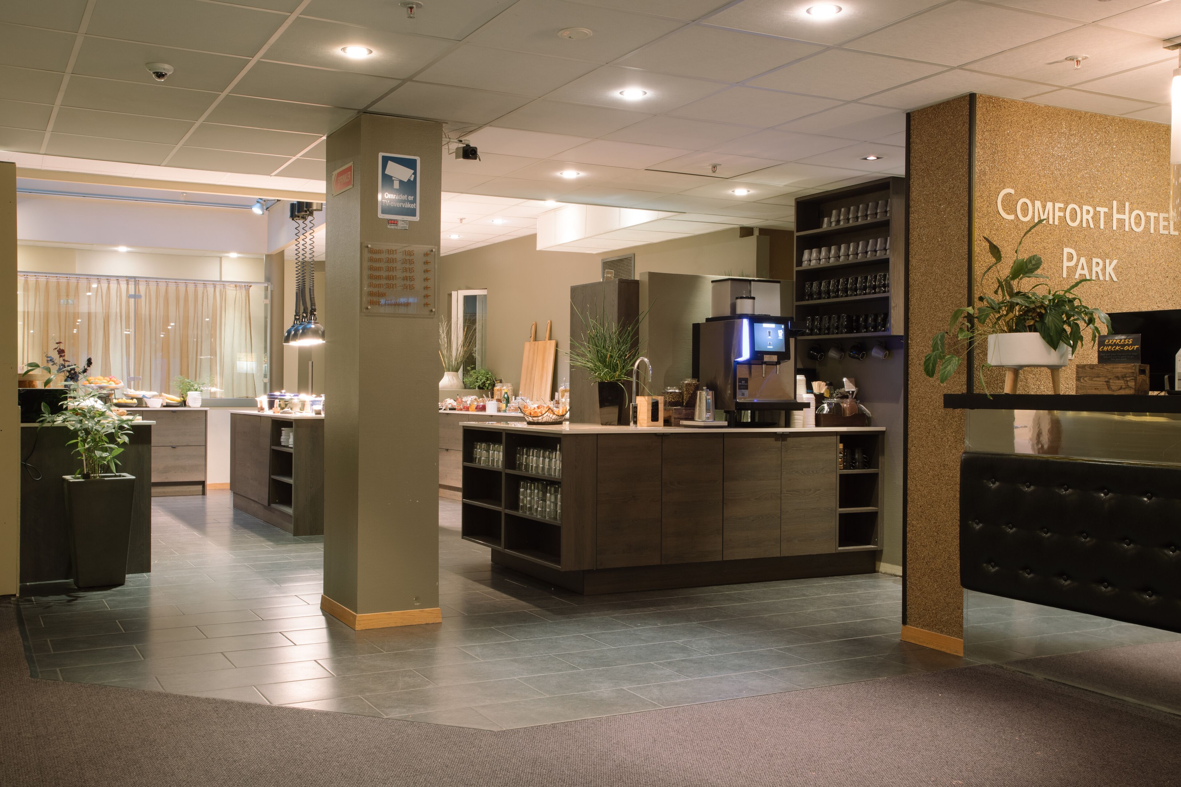 Eine Hotelhalle mit einer Rezeption, einer Sitzecke und einer Wand mit dem Namen des Hotels.