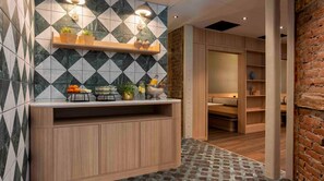 Une salle de bain moderne avec un mur recouvert de carreaux aux motifs géométriques, un meuble-lavabo en bois et un mur d’accent en briques.