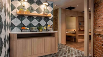A modern bathroom with a geometric tile backsplash, wooden vanity, and a brick accent wall.