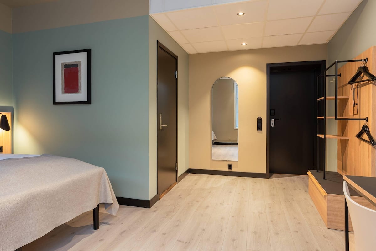 Ein Hotelzimmer mit Bett, Spiegel, Kleiderschrank und Tür.