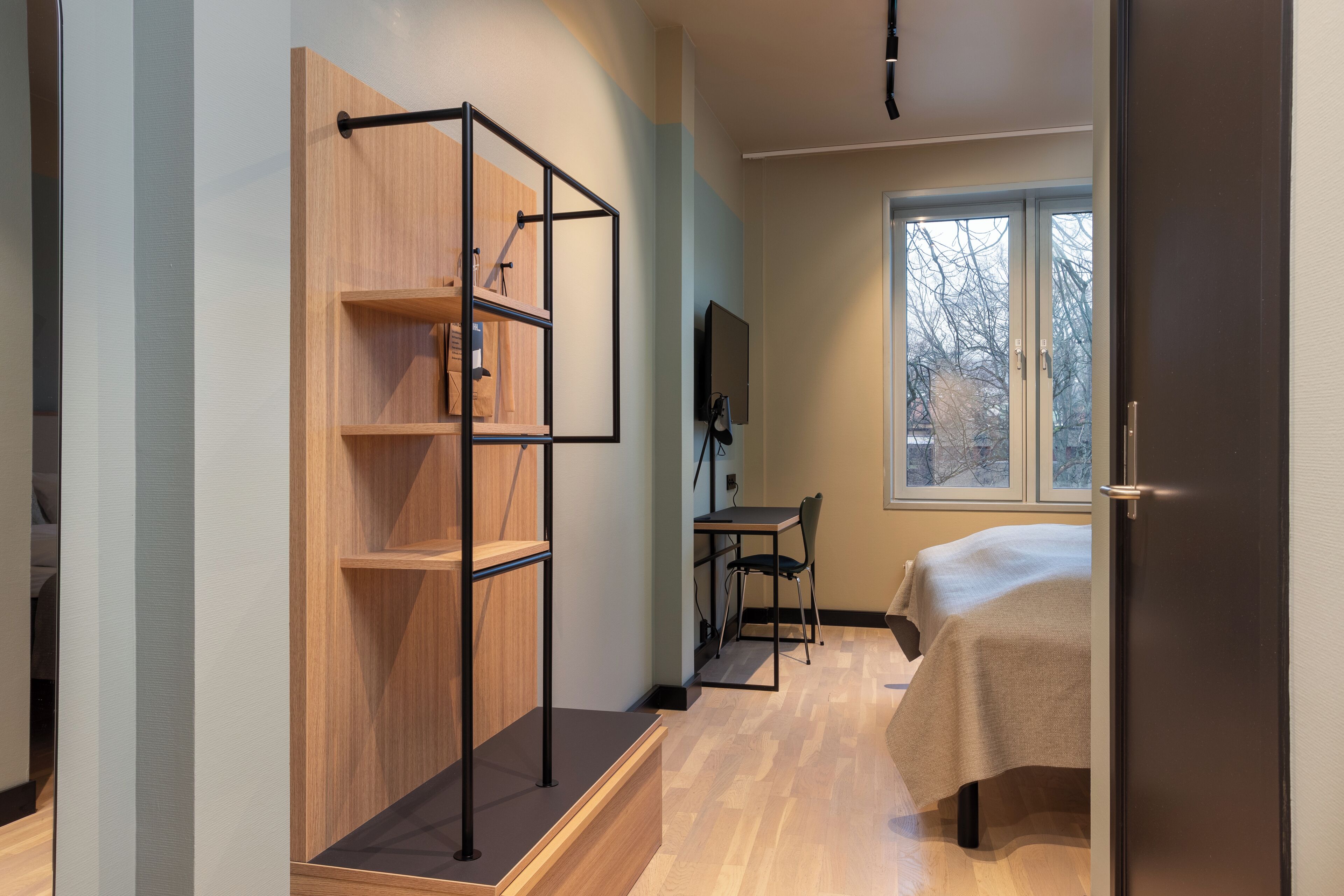 Un dormitorio con cama, escritorio y estantería de madera empotrada.
