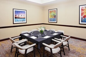 A conference room with a round table, white chairs, and framed artwork on the walls. - Hotel Zessa Orange County Airport, a DoubleTree by Hilton (Santa Ana)