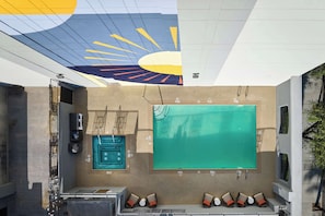 Relax in a spacious room with a large pool, abstract mural, and comfortable seating areas.