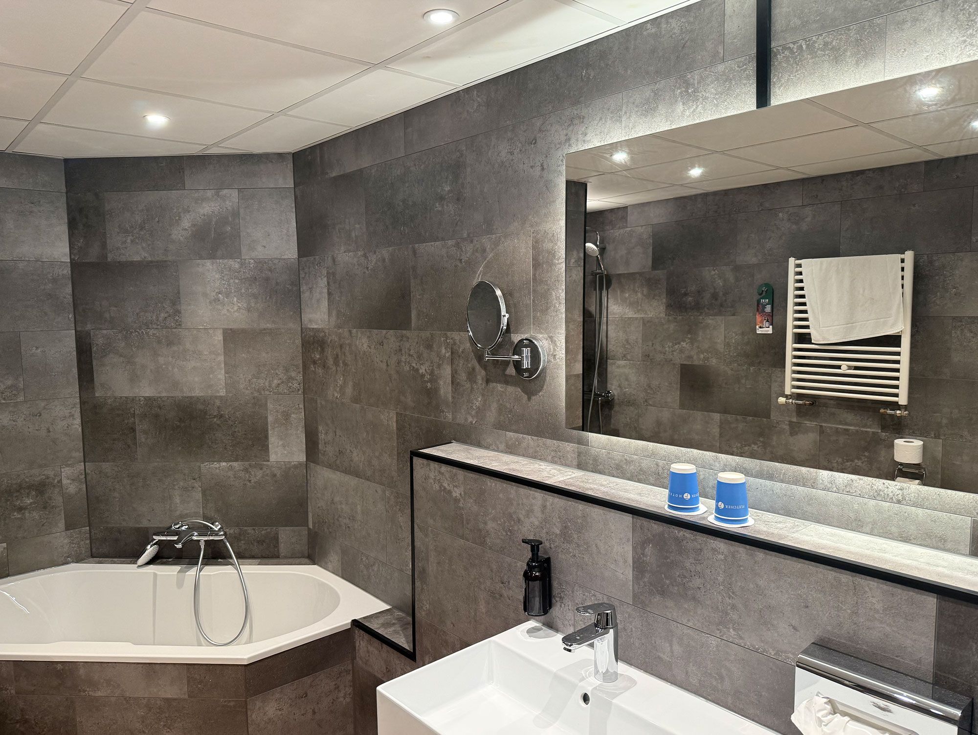 A modern bathroom with a bathtub, a sink, a mirror, and a towel rack.