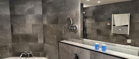A modern bathroom with a bathtub, a sink, a mirror, and a towel rack.