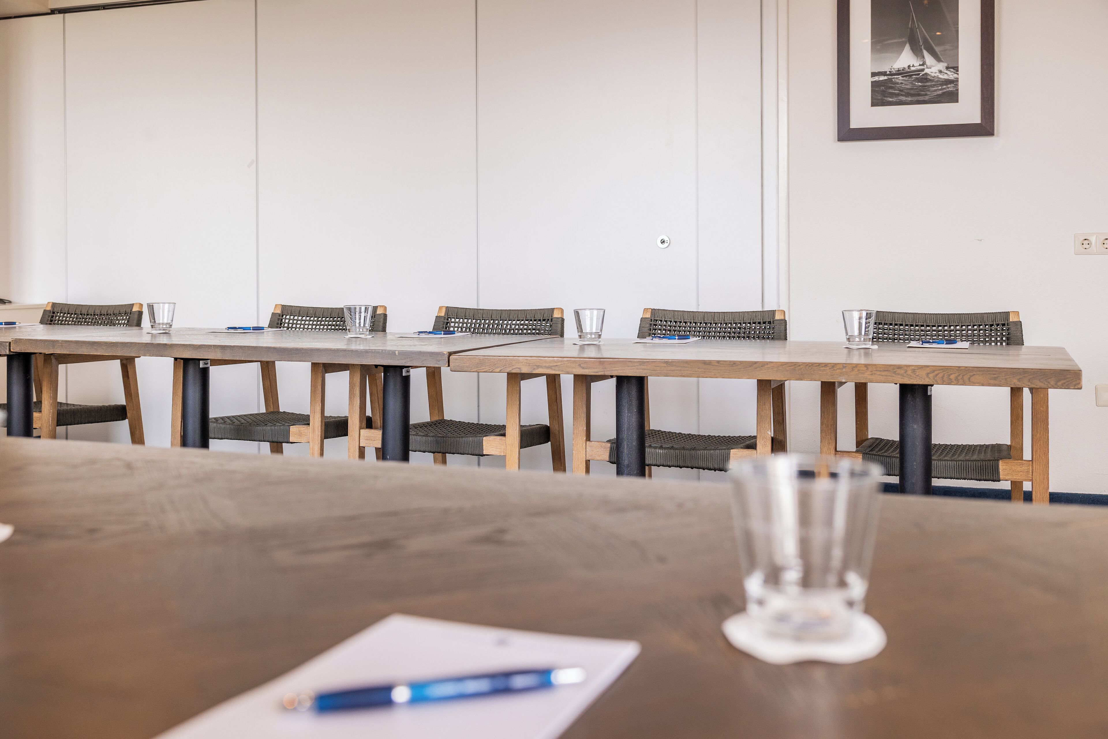 A conference room with a long table, chairs, and a glass of water on the table.