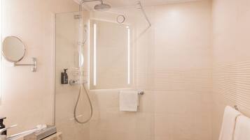 Une salle de bain moderne avec une douche à parois de verre, un miroir rond et un lavabo blanc.