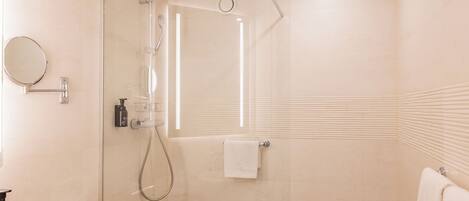 Un bagno moderno con doccia a vetro, uno specchio rotondo e un lavandino bianco.
