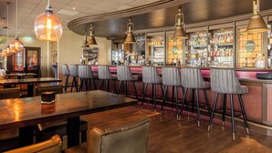 Een bar met houten tafels, barstoelen en hangende吊灯.