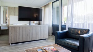 Een moderne hotelkamer met een flatscreen televisie, een houten bureau, een leren bank en een bijzettafeltje met tijdschriften.
