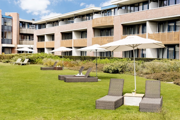 A hotel courtyard with outdoor seating and a building with balconies.