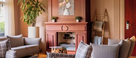 A living room with a fireplace, sofas, a coffee table, and a potted plant.