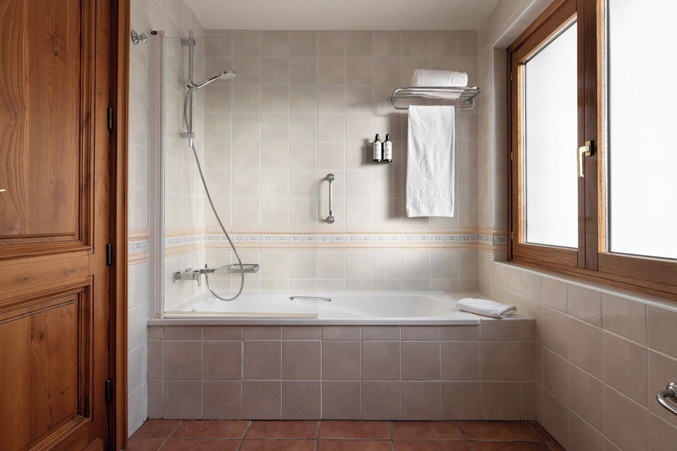 A bathroom with a bathtub, shower, and a window.