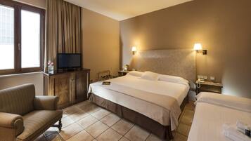 A hotel room with a bed, a TV, a desk, and a chair.