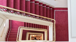 A grand staircase with red carpeted steps and ornate golden railings. - Dorma Alfonso VIII (Plasencia)